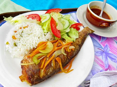 Whole fried fish topped with pickled vegetables, with rice and salad